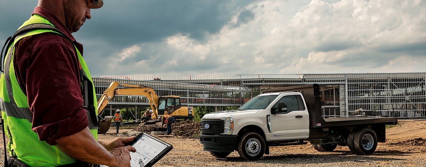 Foreman using a tablet near a white 2024 Ford F-350 XL Chassis Cab